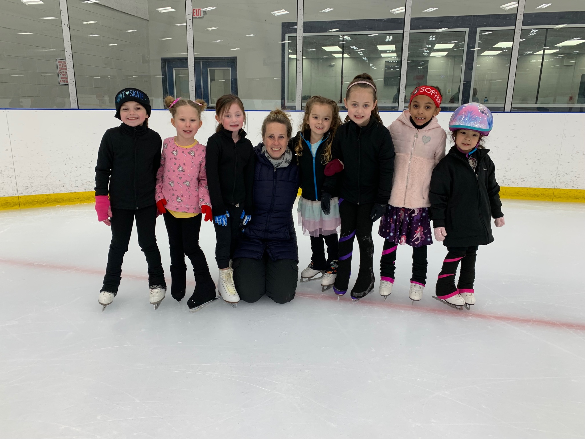 Amy Griffith (center) with members of the Tuesday with Amy skate club (kneeling at center ice).