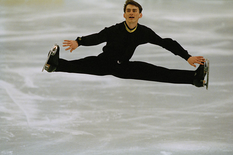 Todd Eldredge in all black mid-air in a split.