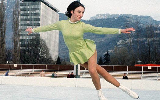 Peggy Fleming performs a crossover while wearing a green dress at the 1968 Olympic Games.