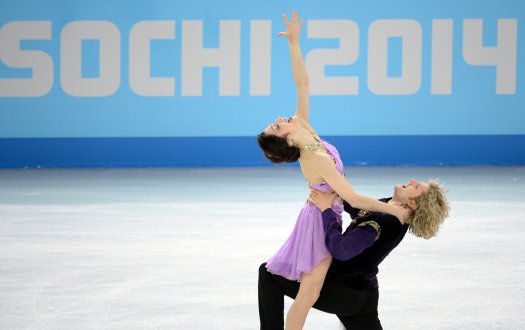 Meryl Davis, wearing pink, reaches to the sky as Charlie White holds her from his knees, at the end of their program.