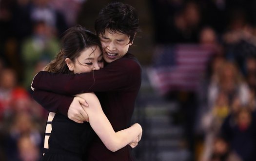 Maia and Alex Shibutani embrace on the ice after completing their program, as fans cheer in the background.