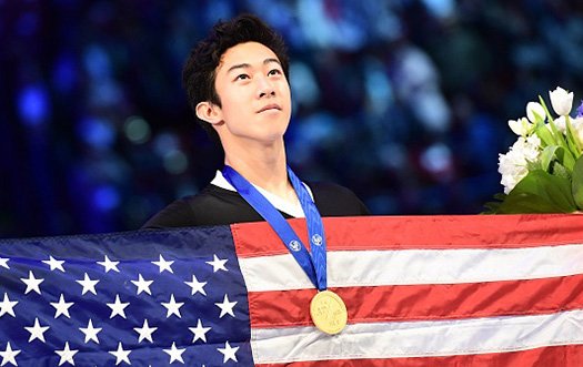 Nathan Chen looks towards the sky with a gold medal around his neck and an American flag in his hand. 