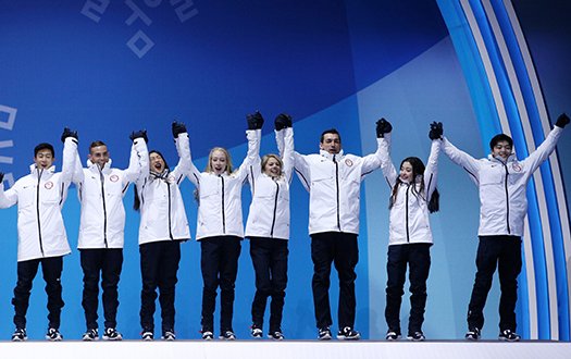 The Olympic Team event participants cheer while holding hands as they are awarded their medals.