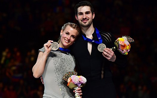 MAdison Hubbell and Zachary Donohue smile for the camera with medals in hand from the podium at the 2019 World Championships.