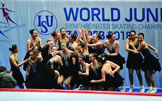 A group of skaters all jump up and down in the Kiss and Cry after receiving their score.