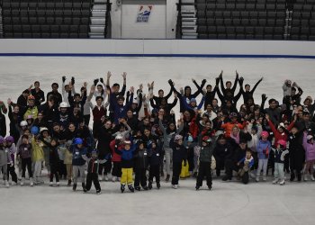 Dozens of skaters stand in the middle of the SC of Boston Tenley Albright Performance Center as part of World Ice Skating Day.