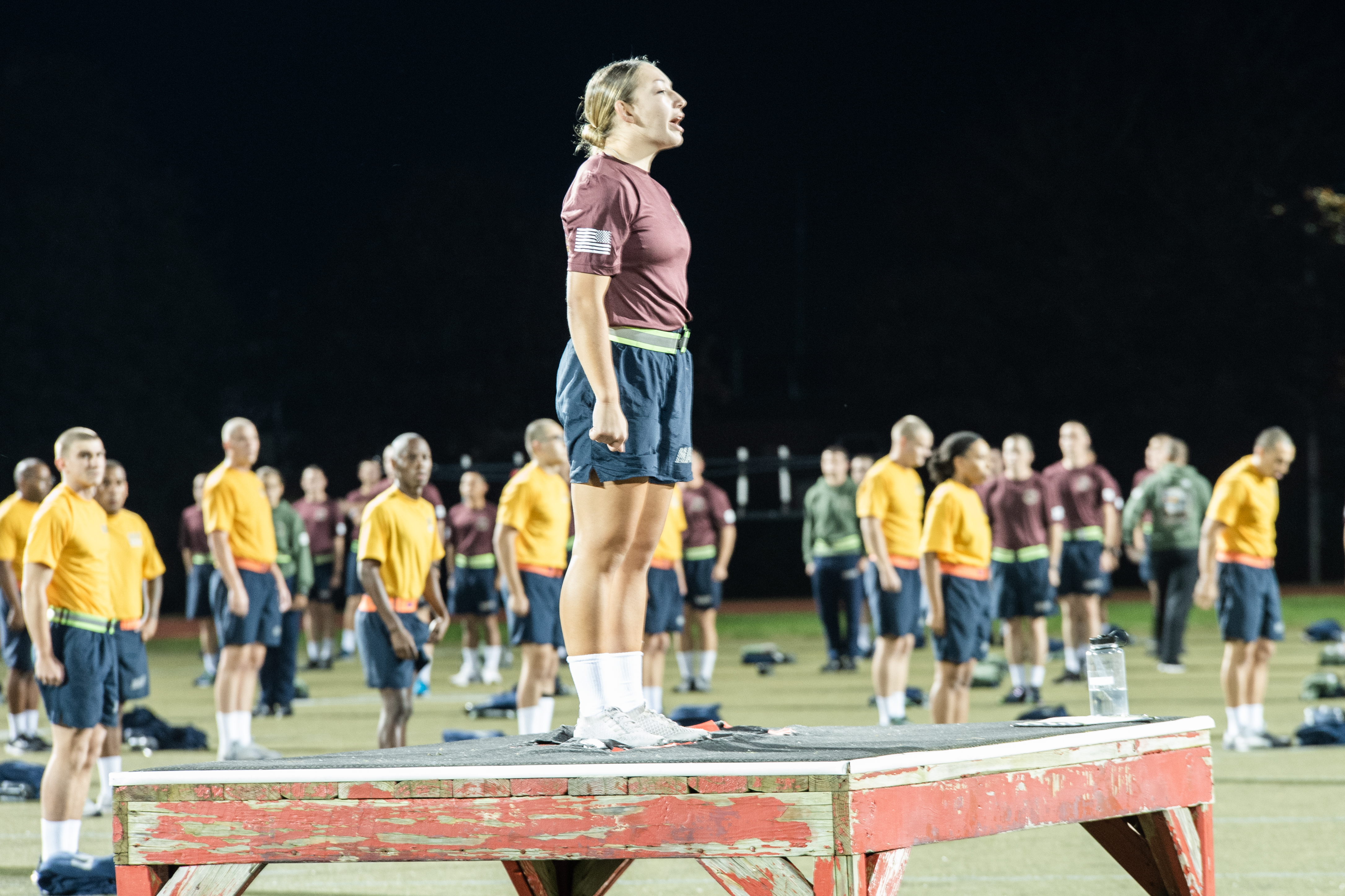 Casey Ouellette stands on a platform among Navy cadets.