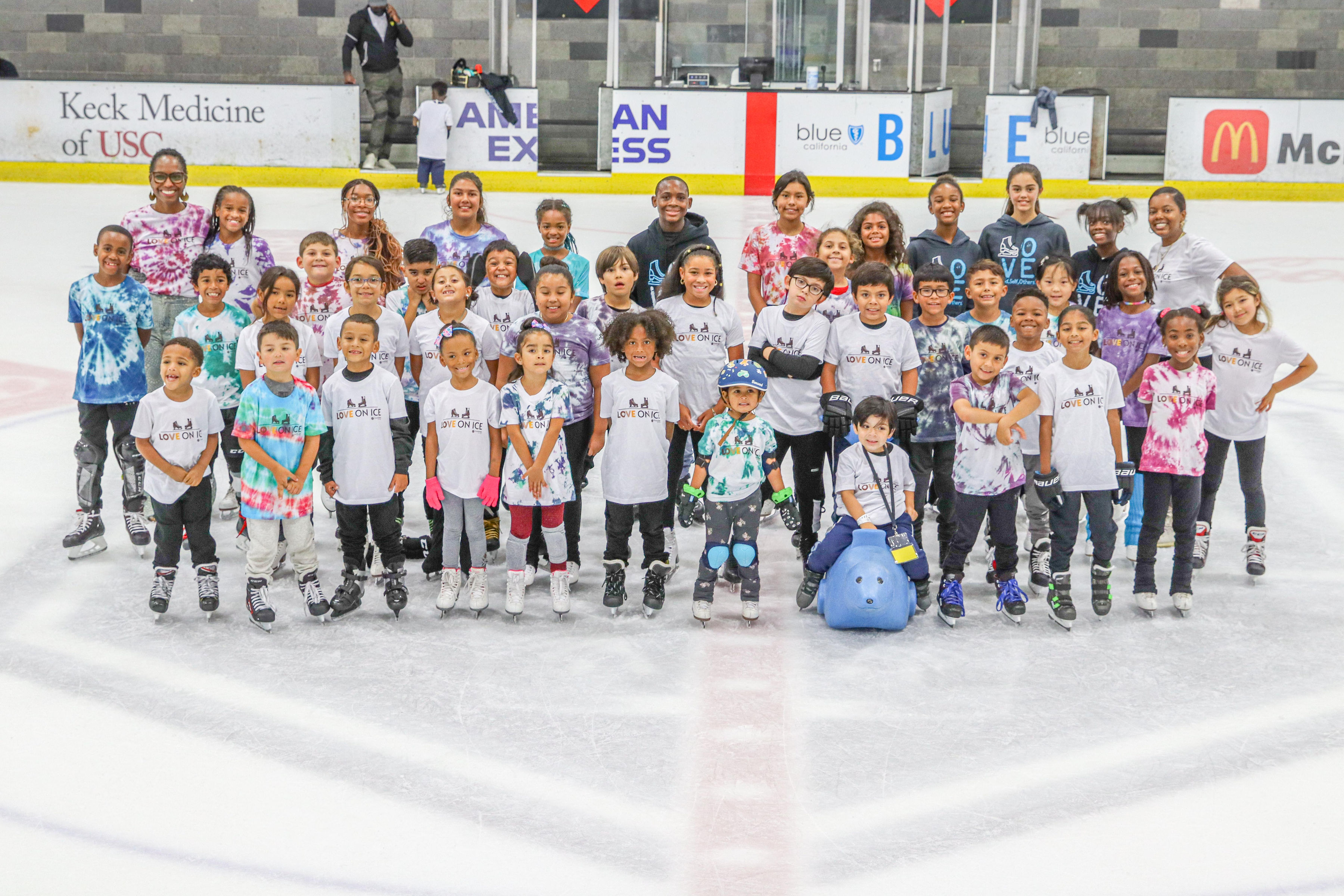 A large group of young skaters on the ice together.