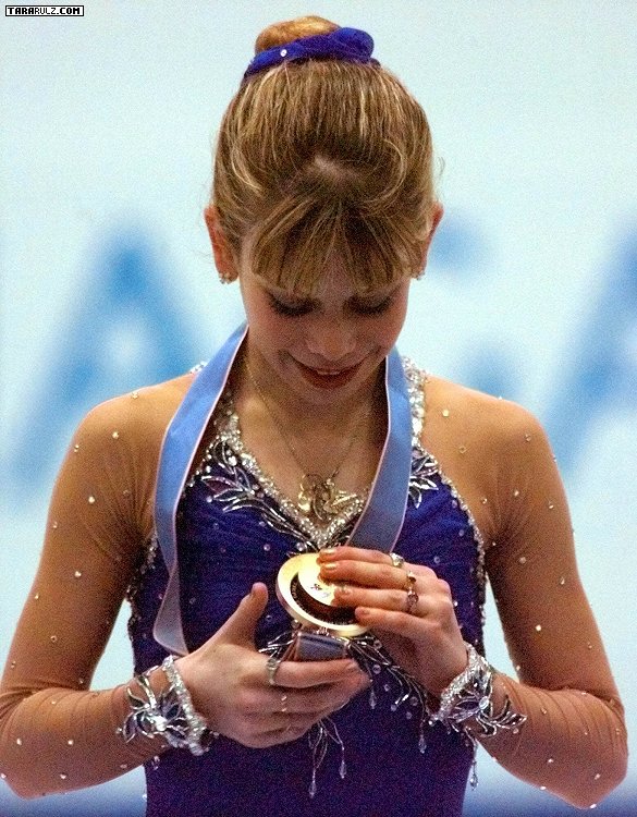 Tara Lipinski, wearing her competition dress, admires her Olympic gold medal.