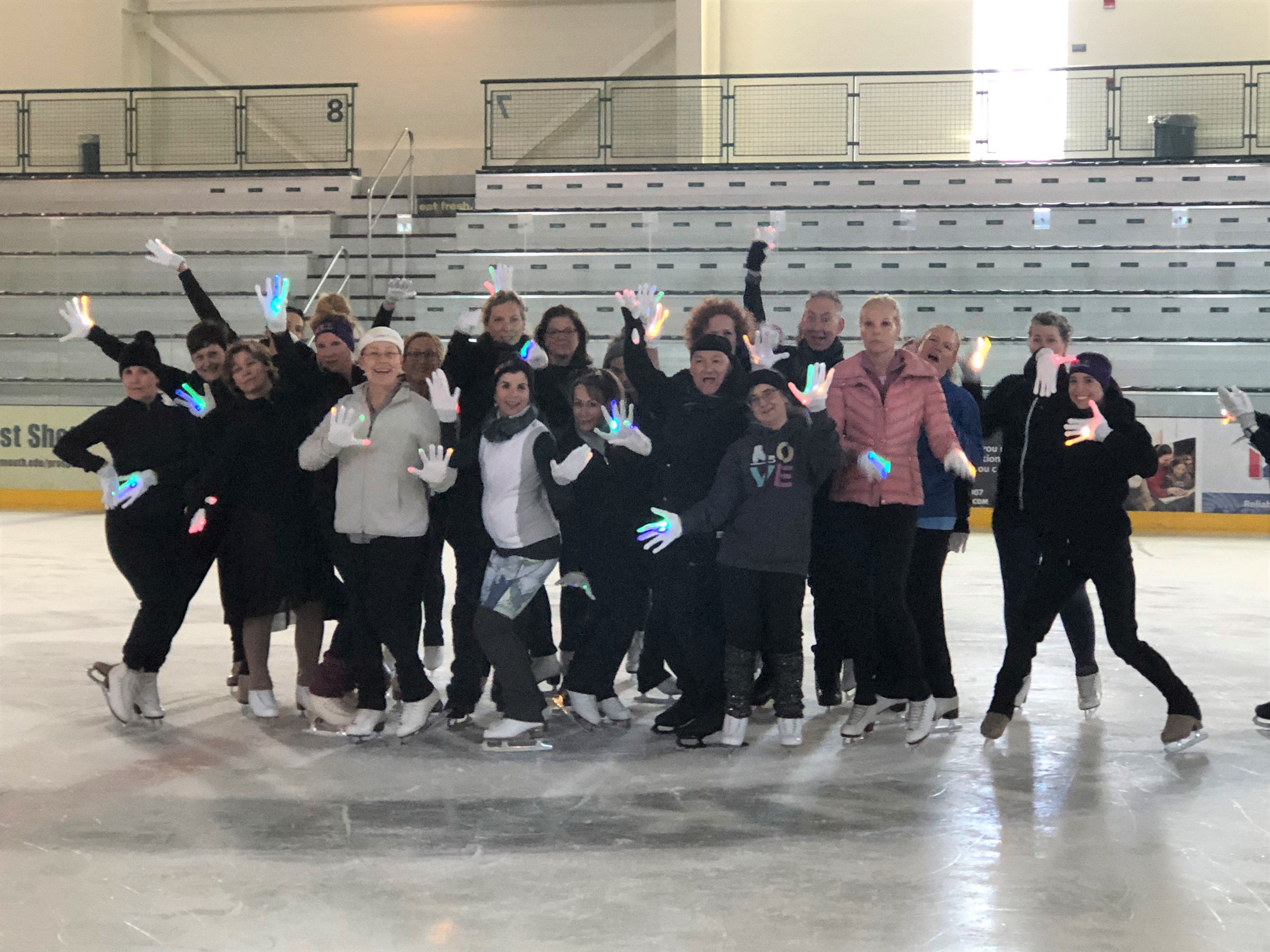 The RiverWalk Adult Camp skaters and coaches pose in a funny position as a group.