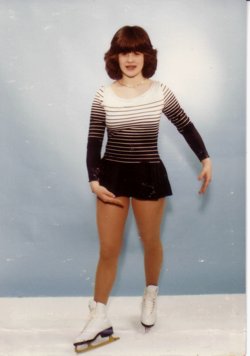 Cindy Duvall posing in figure skates and a short skating dress.