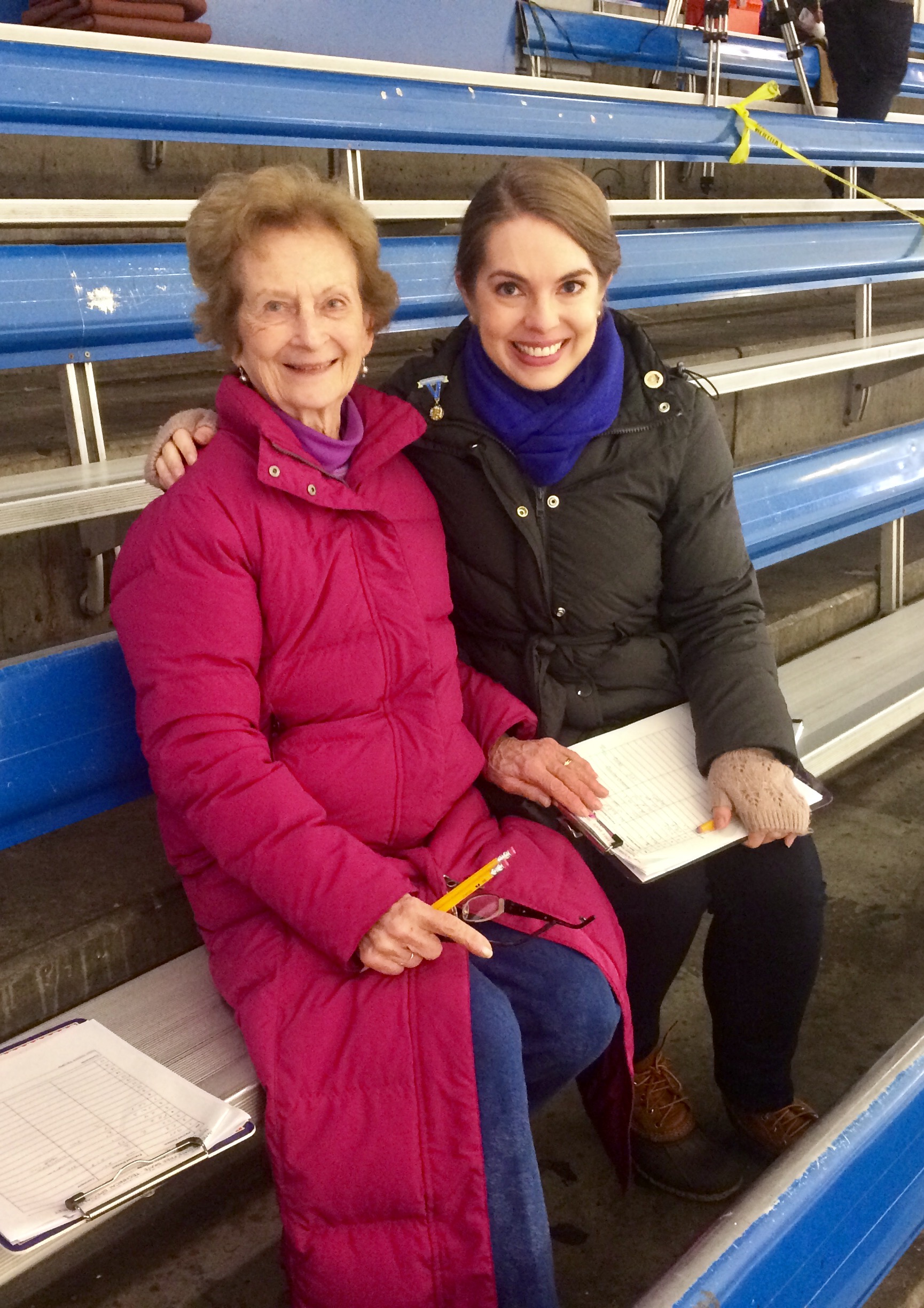 Ann Fauver and Lauren O'Toole sitting in the stands of an ice rink.