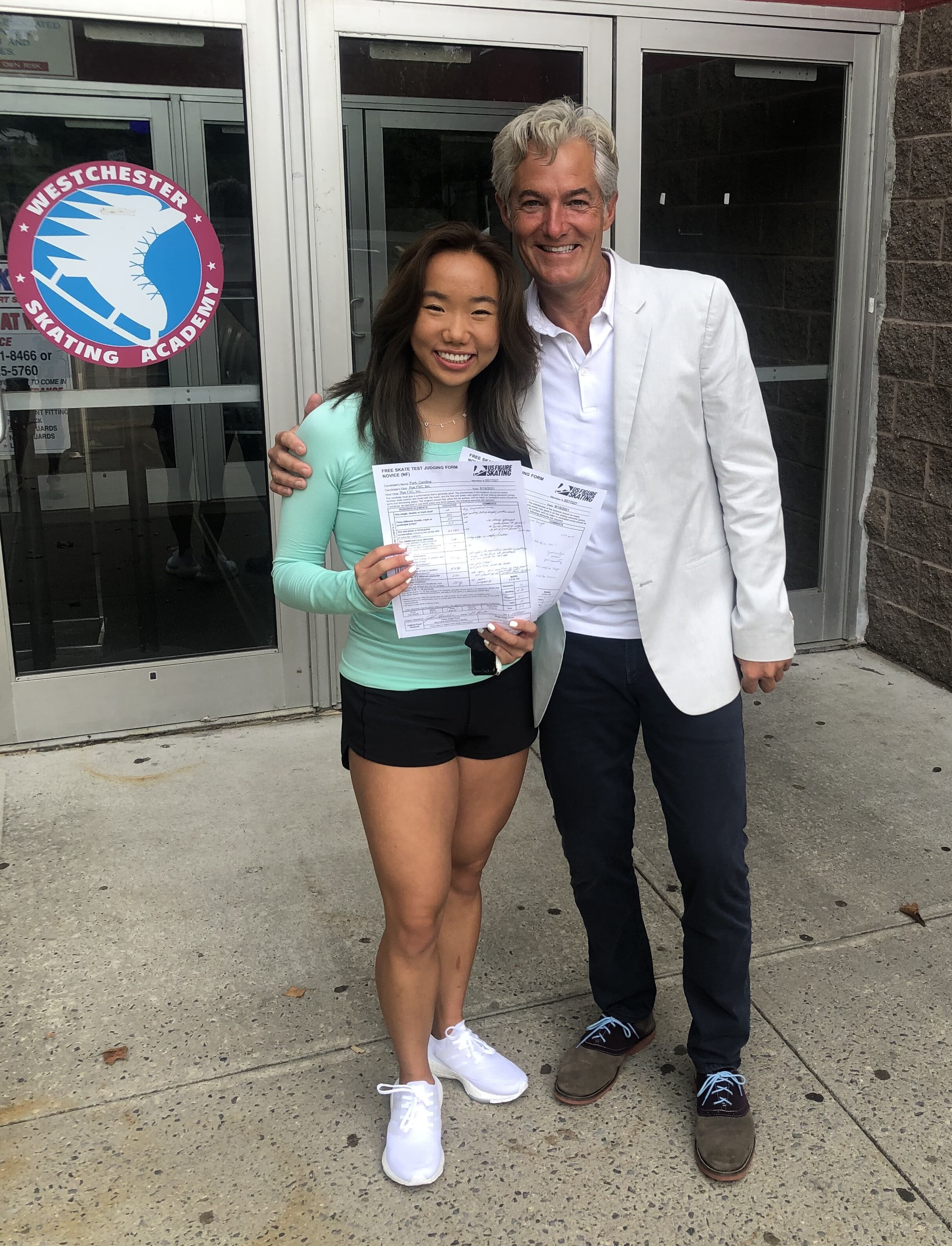 Caroline poses with coach Tim Covington as she shows off passed tests for judging.