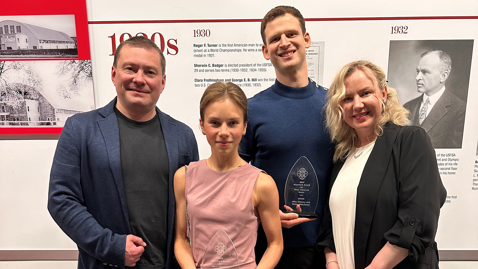 Coaches Aleksey Letov and Olga Ganicheva flank their skaters Alisa Efimova and Misha Mitrofanov, who hold a glass trophy as the winners of the Skating Club of Boston's most improved skaters of 2024.