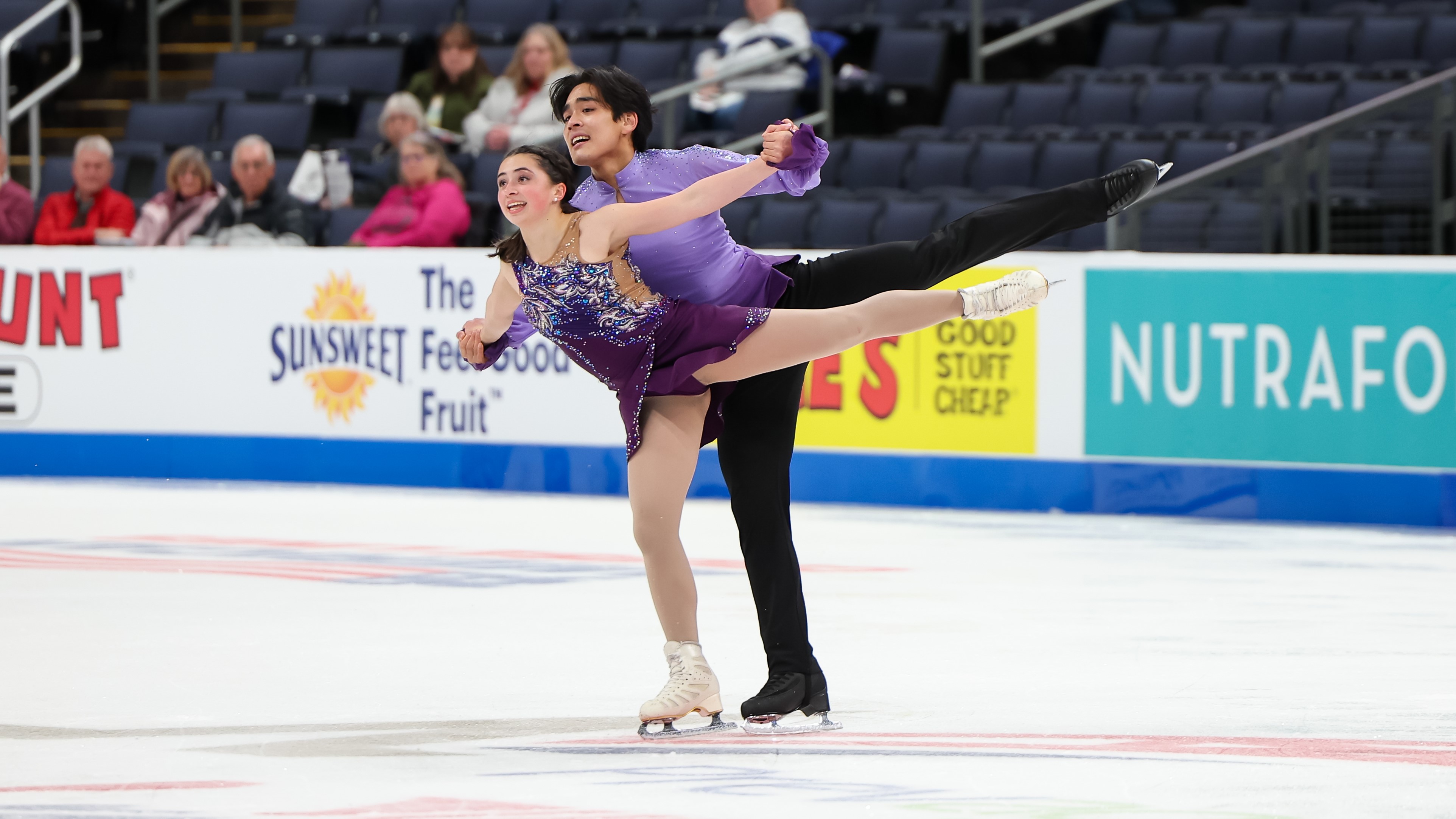 Dressed in purple, Olivia Flores and pairs partner Luke Wang skate side by side in competition.