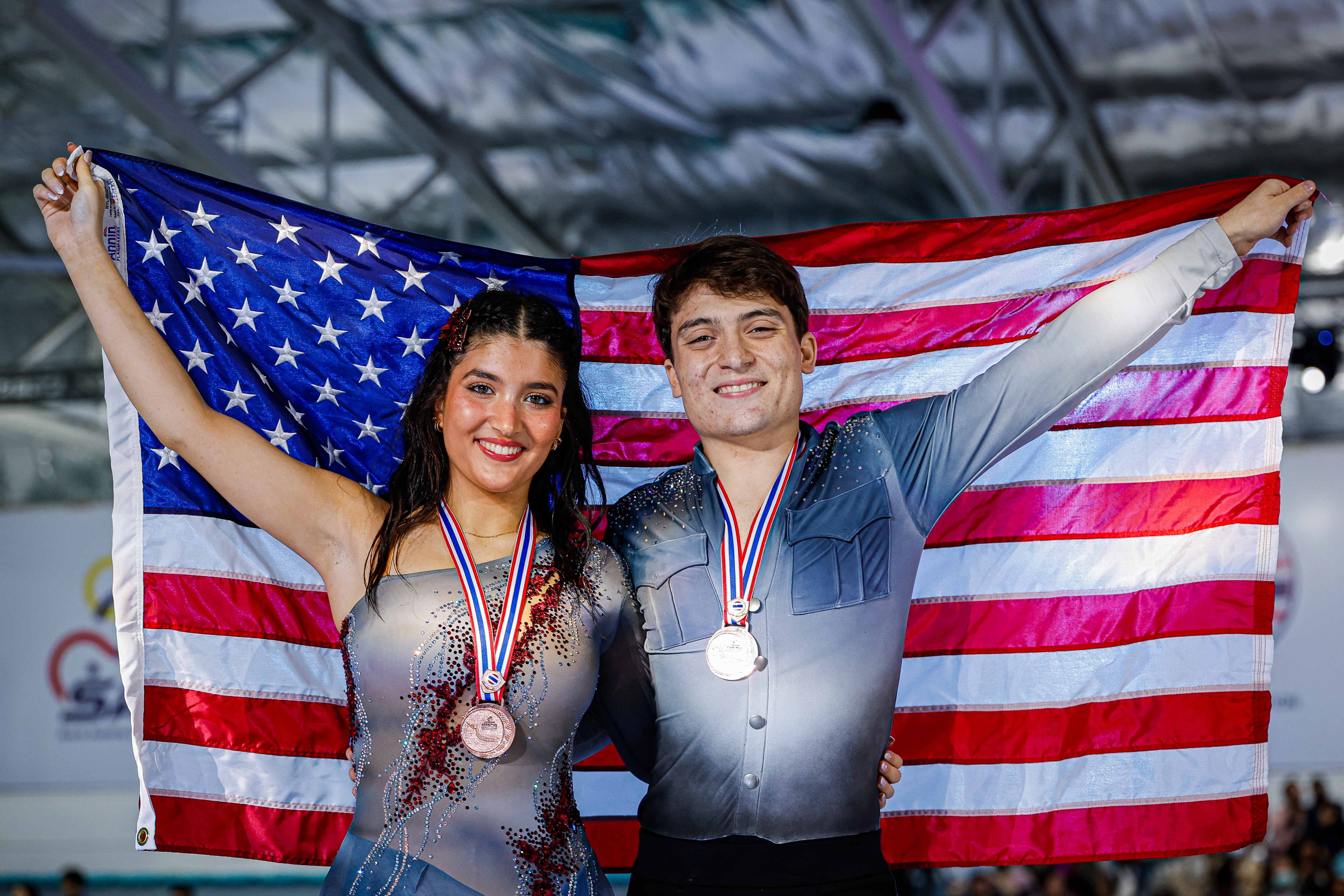 Draped in the American flag, Elliana Peal and Ethan Peal showcase their bronze medals.