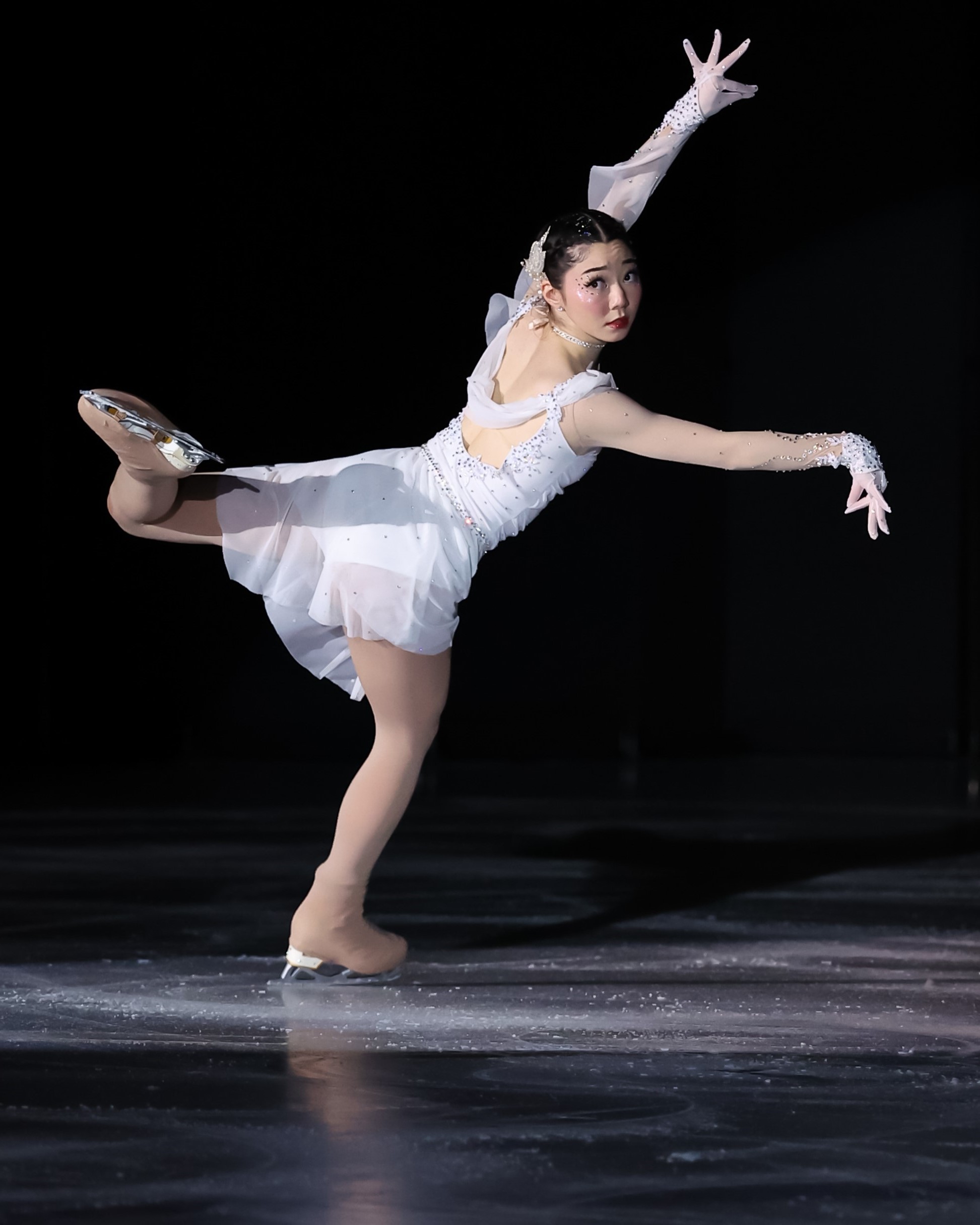 Koko Hirano, wearing a flowing white dress, displays her grace on the ice.