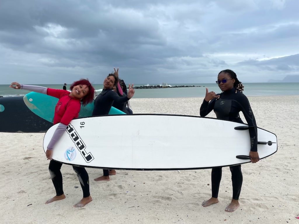 Members of Figure Skating in Harlem hold a surfboard before their surfing lesson with the 9Miles Project