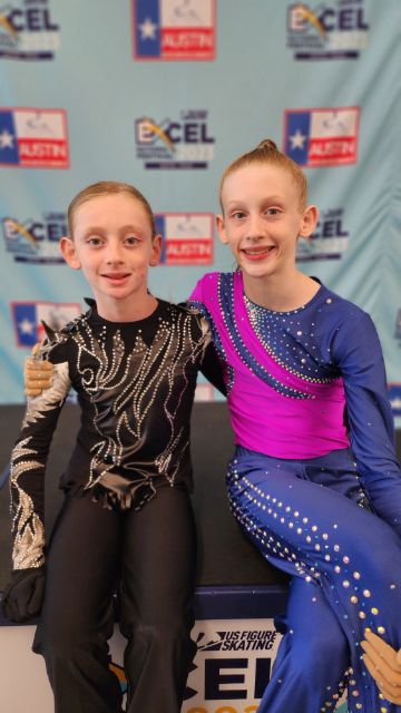 The Cavaliere siblings pose with their arms around each other. Both are young boys wearing their skating costumes