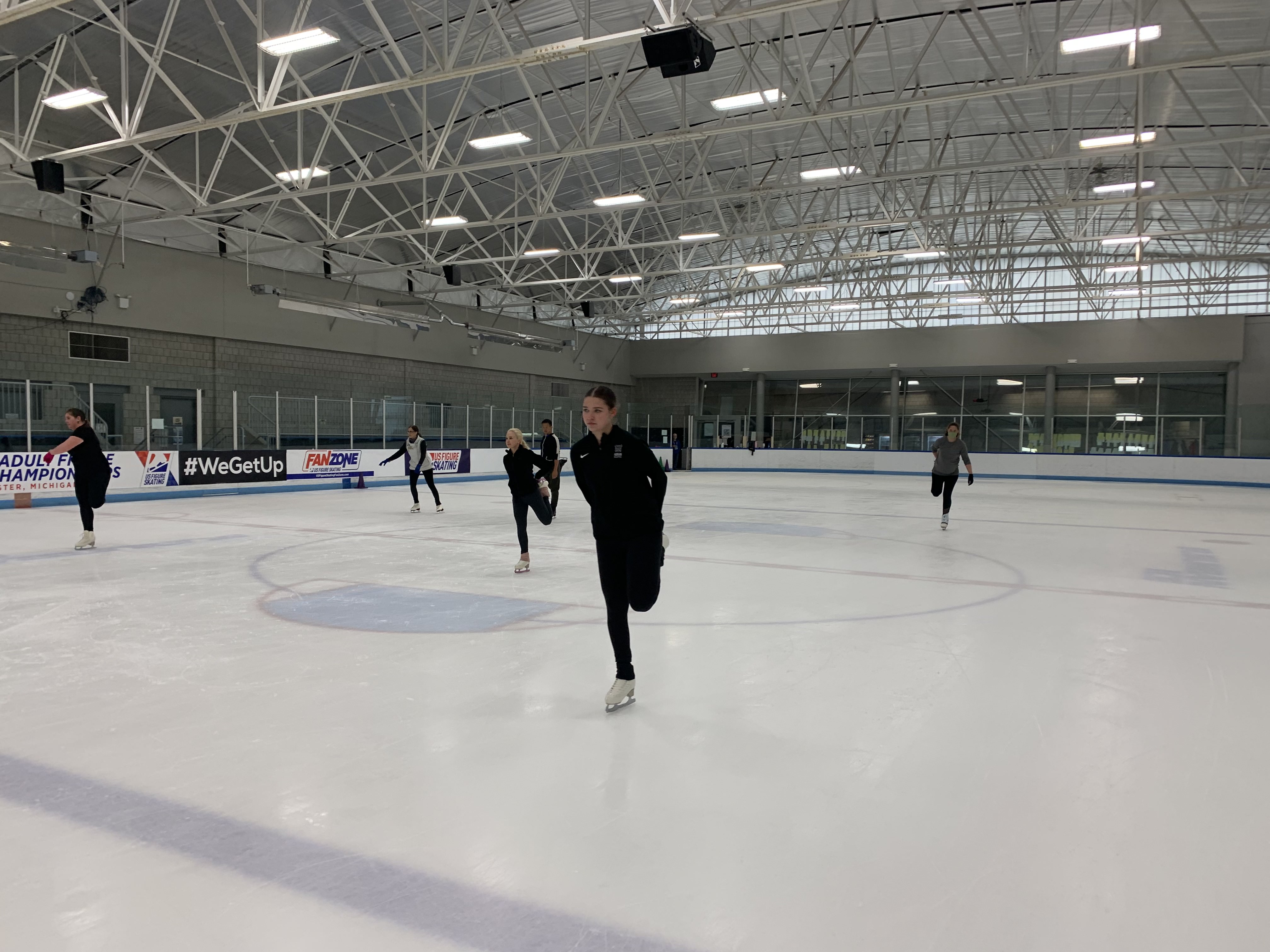 Skaters warm up on the ice with quad stretches