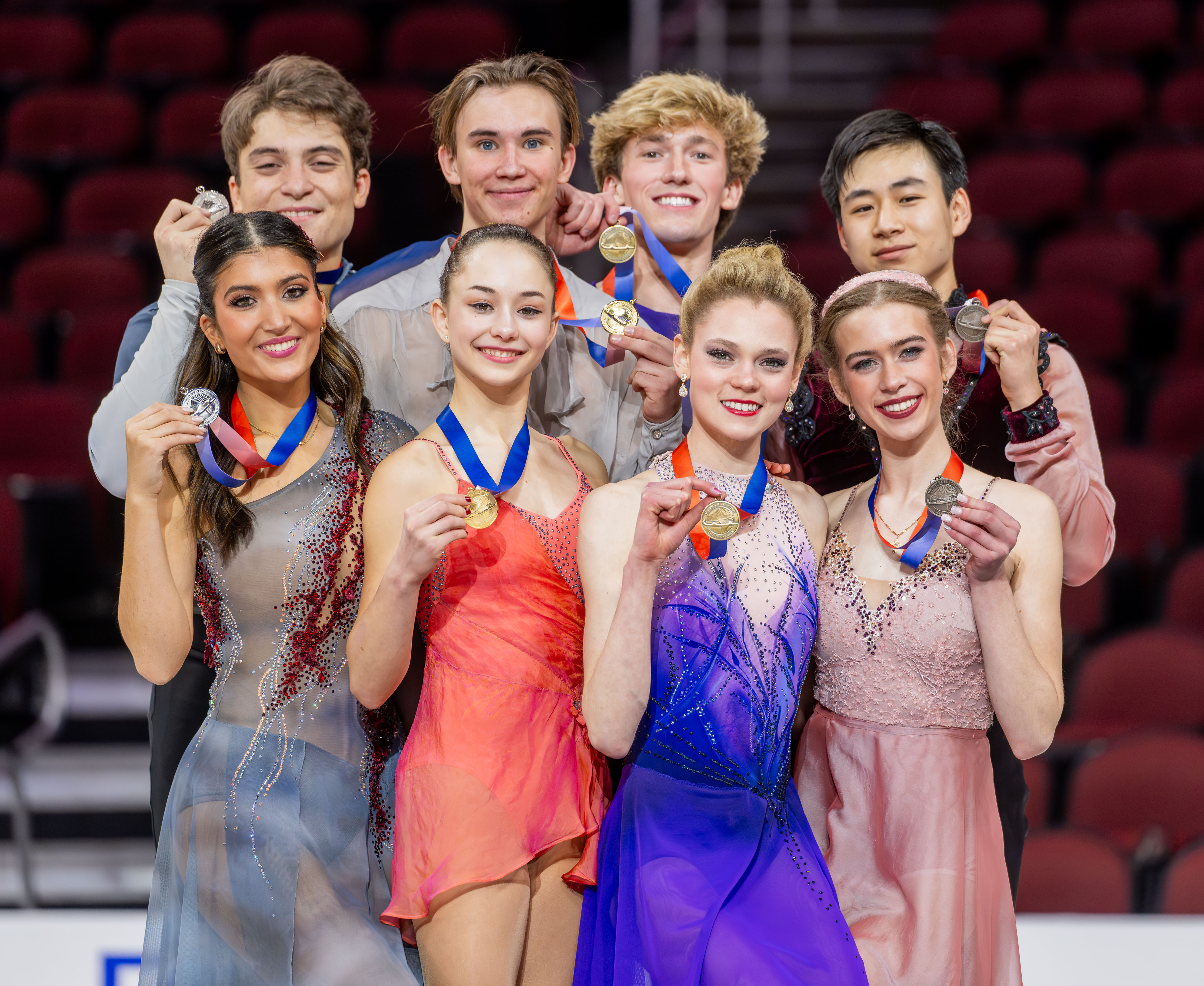 The junior ice dance medalists stand together on the podium, the woman standing in front of the man.