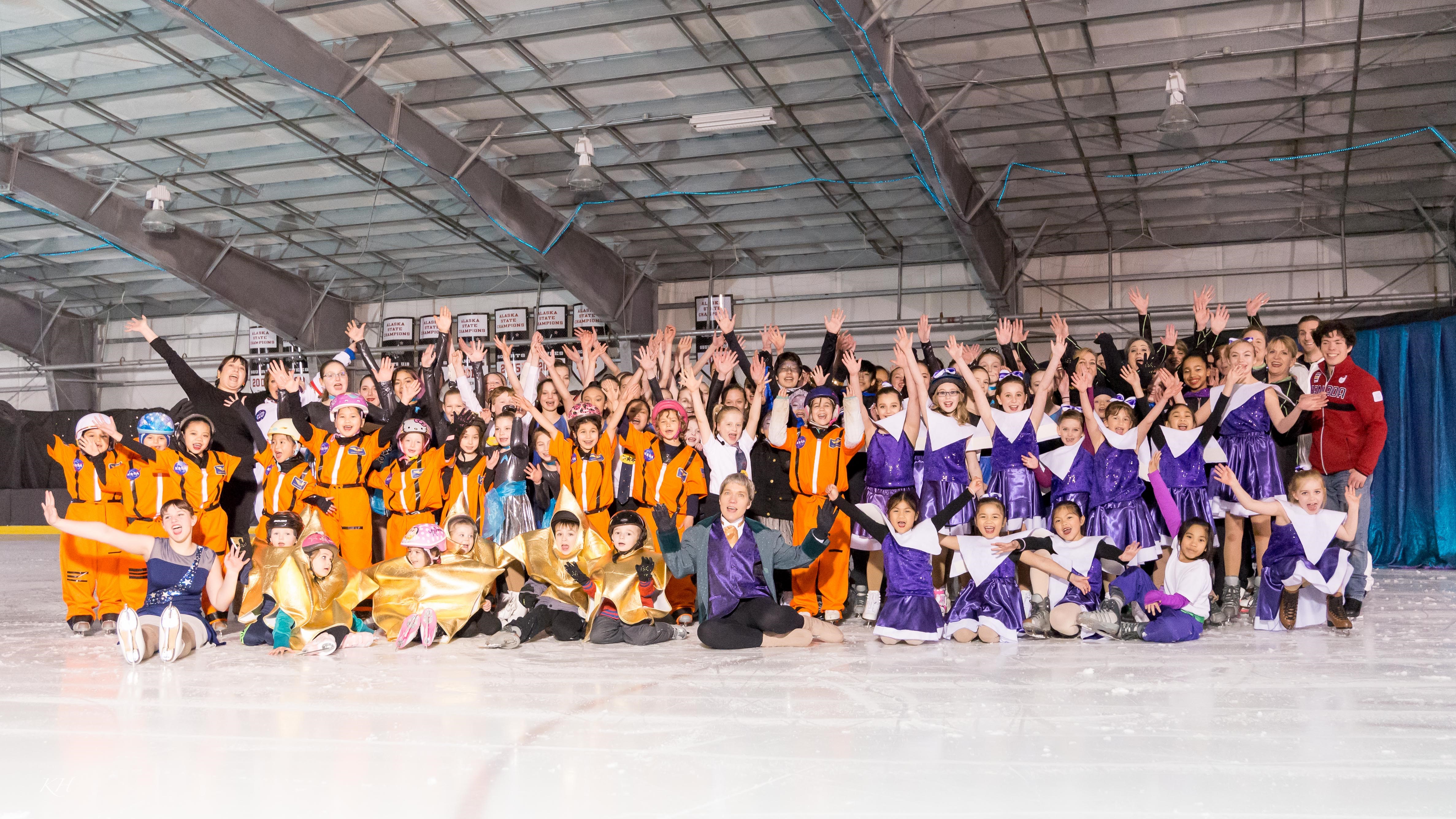 A group photo of Juneau figure skaters wearing matching orange shirts. 