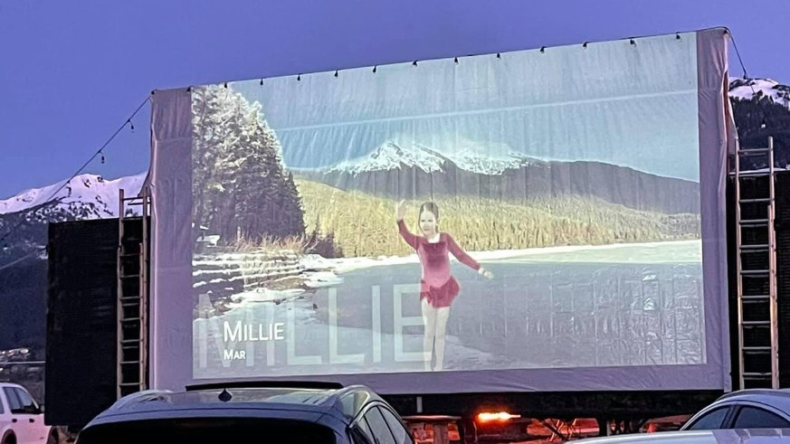 The drive-in movie screen feature a figure skater performing with a mountain backdrop.