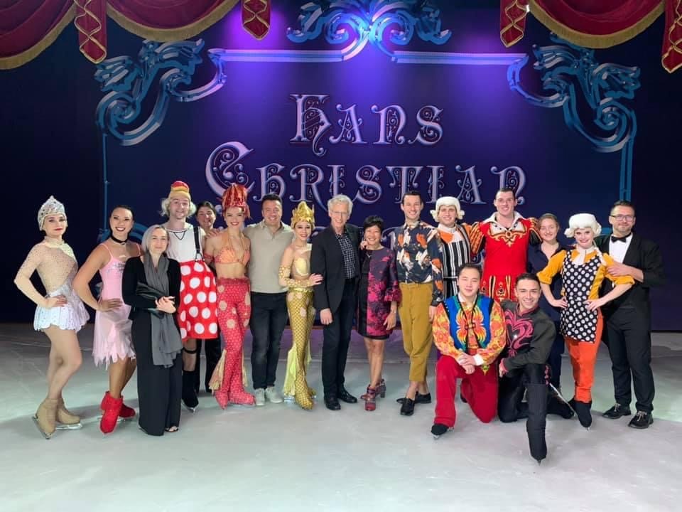 A cruise ship skating show group poses on the ice with Sarah Kawahara.