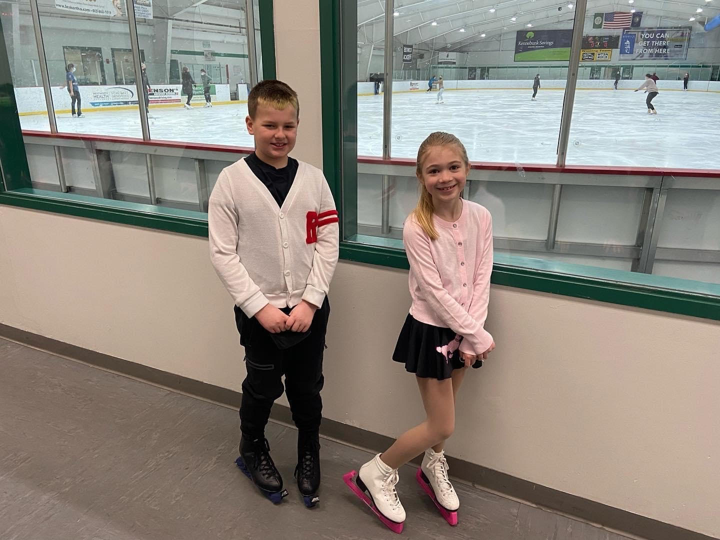 Mason and Paige in their skating costumes by the boards.