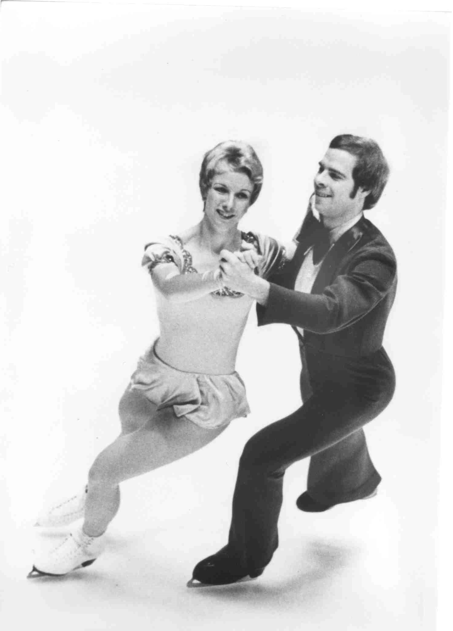 Jim Millns and Colleen O'Connor skate together in hold. Photo is in black an white.