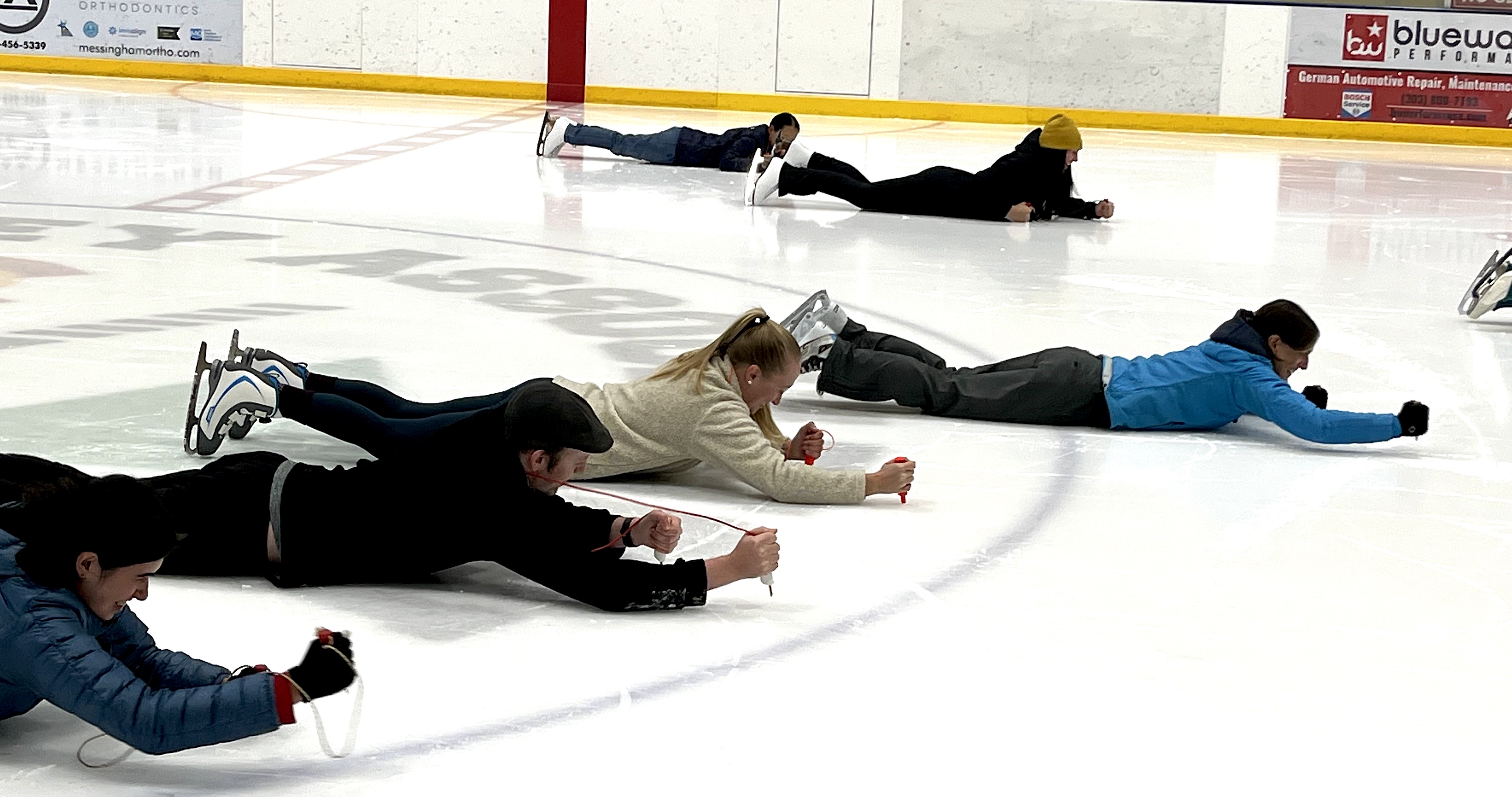 Laura lays on the ice showing people how to use safety climbing equipment