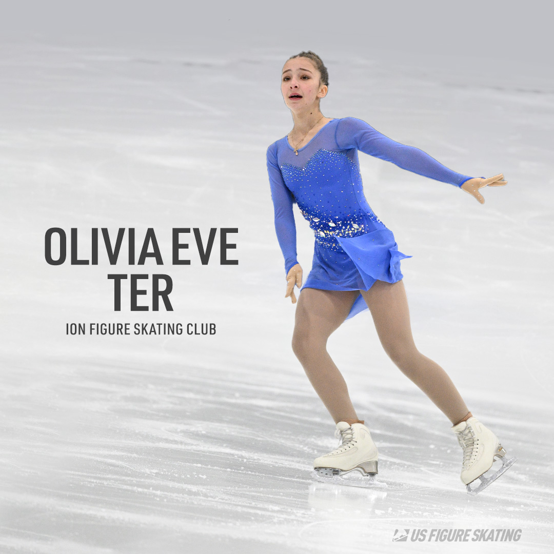 Photo of Olivia Eve Ter wearing a long sleeve light blue skating costume. She is a young girl with brown hair tied back in braids. 