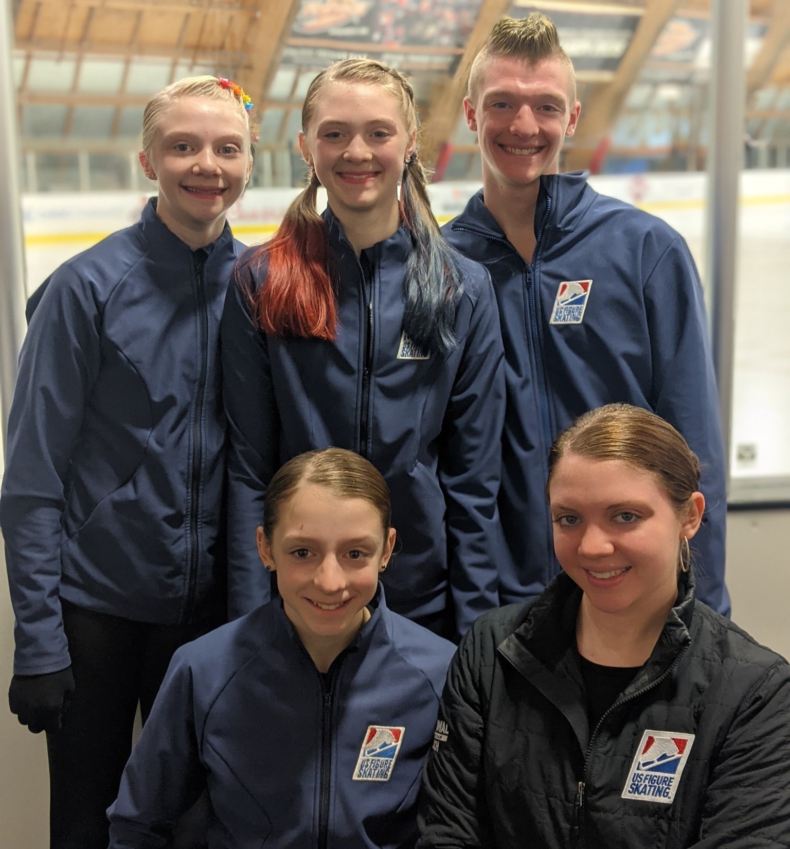 The five members of the Rudedenman family stand rinkside together in their blue U.S. Figure Skating jackets.  