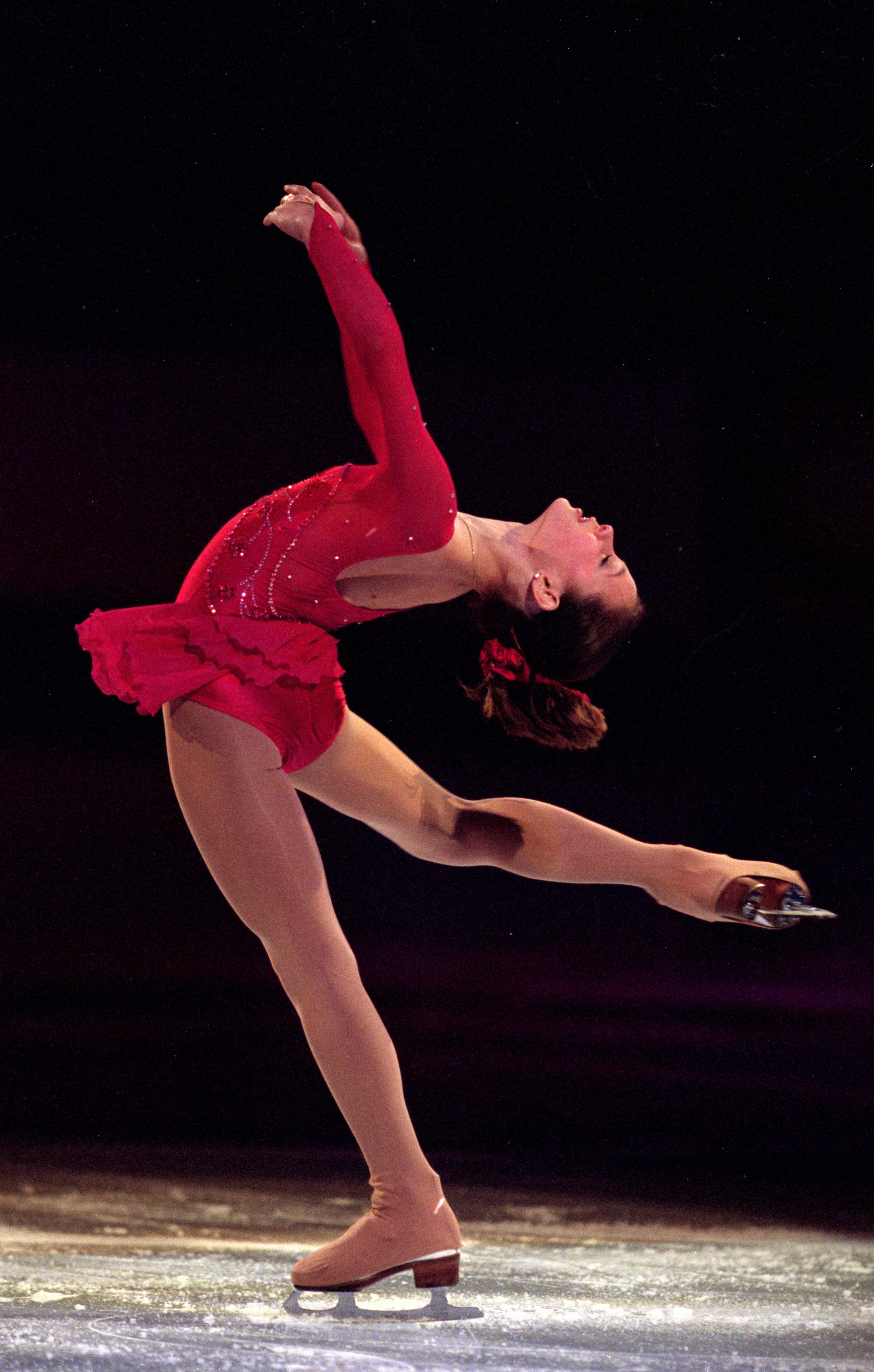 Sasha Cohen in a layback wearing a red dress under the spotlight.