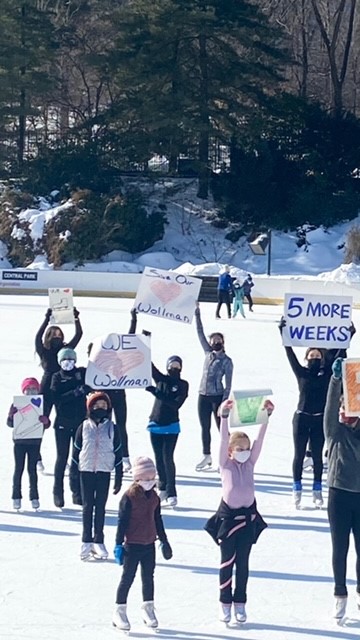 Skaters glide across the ice at Wollman Rink holding up signs protesting the early rink closure.