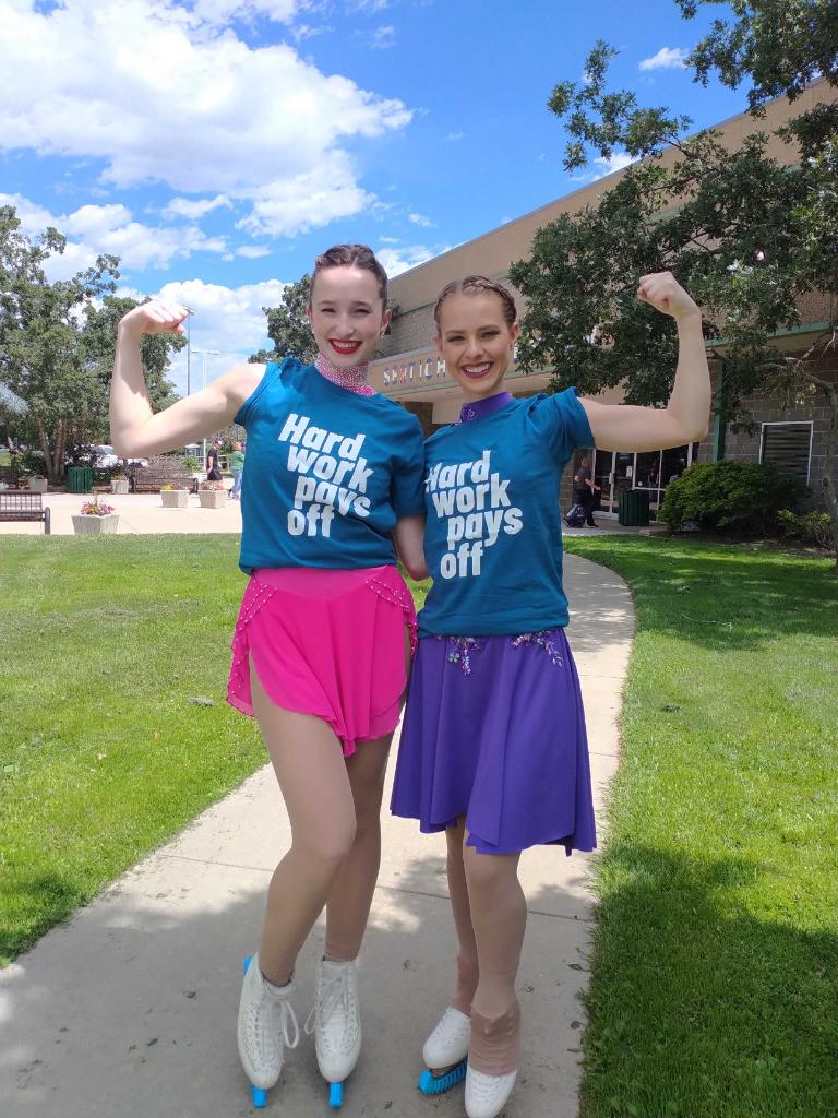 Hunter Widvey and a friend in skating dresses with blue t-shirts that say "hard work pays off."