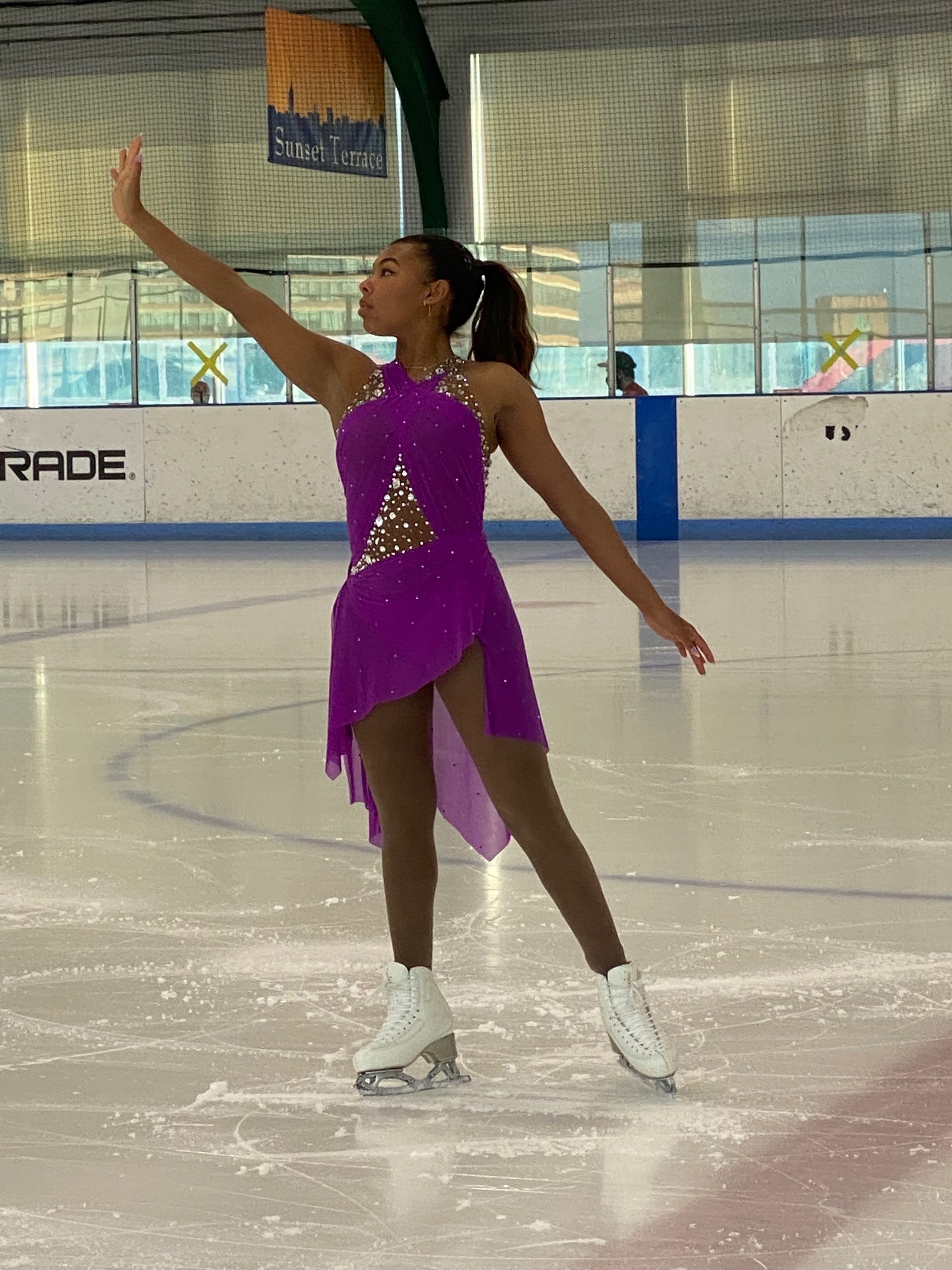 Starr Andrews poses on the ice in a purple dress.