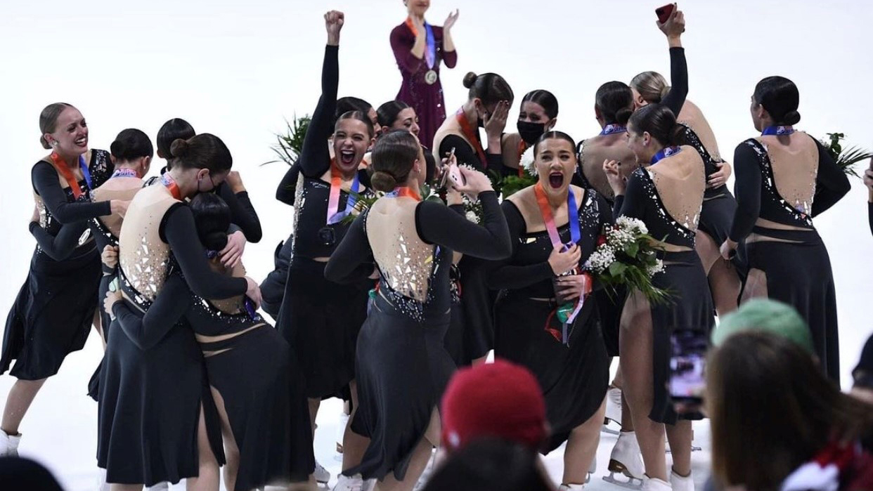 The Miami University synchronized skating team celebrates after receiving medals, hugging and cheering.