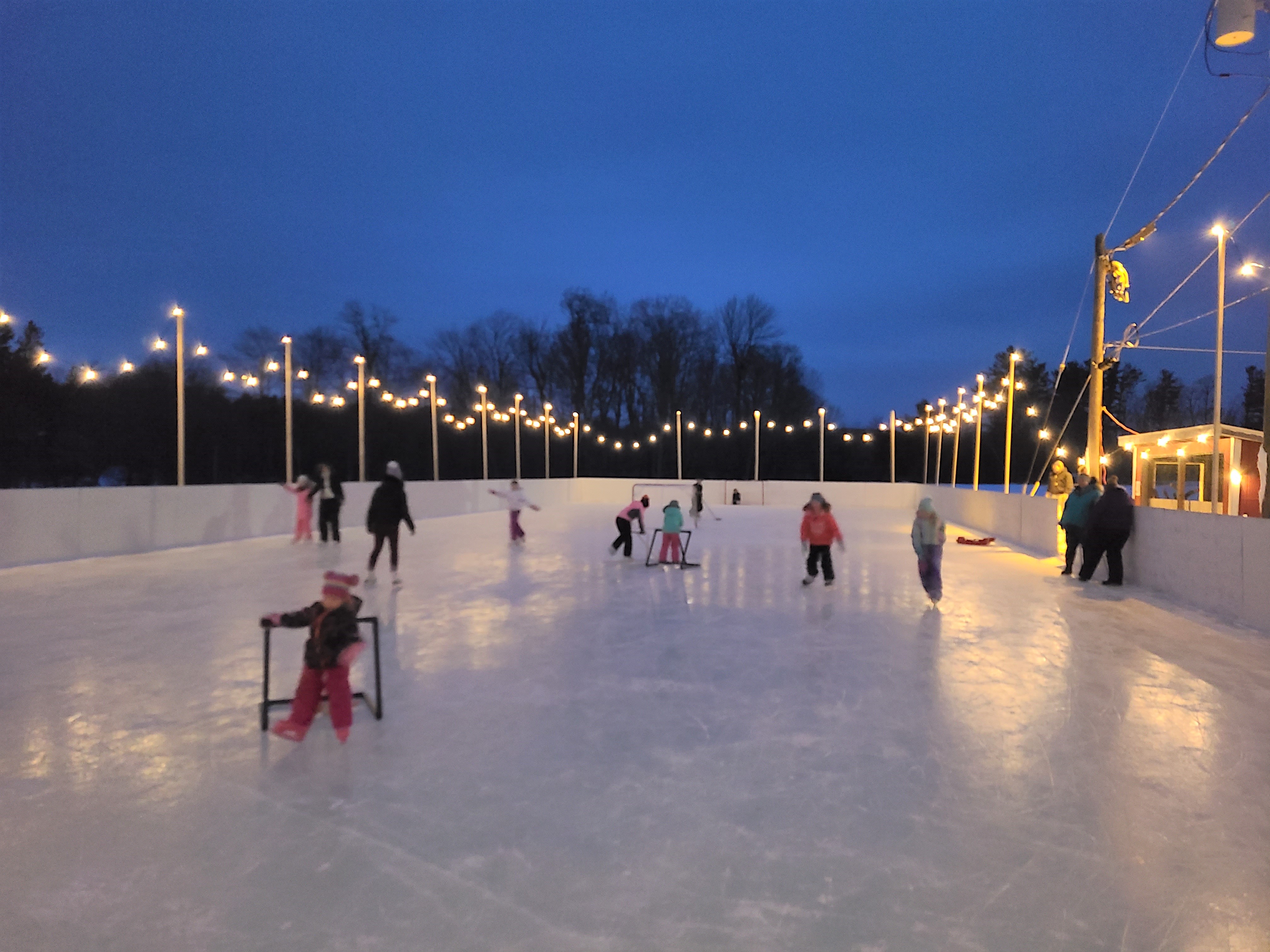 An outdoor ice rink at night with lights above.