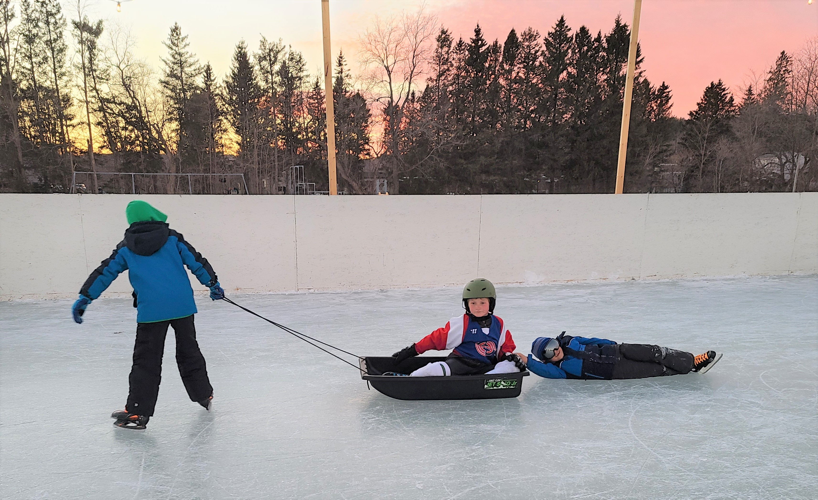 A kid gets pulled on a sled on the ice.