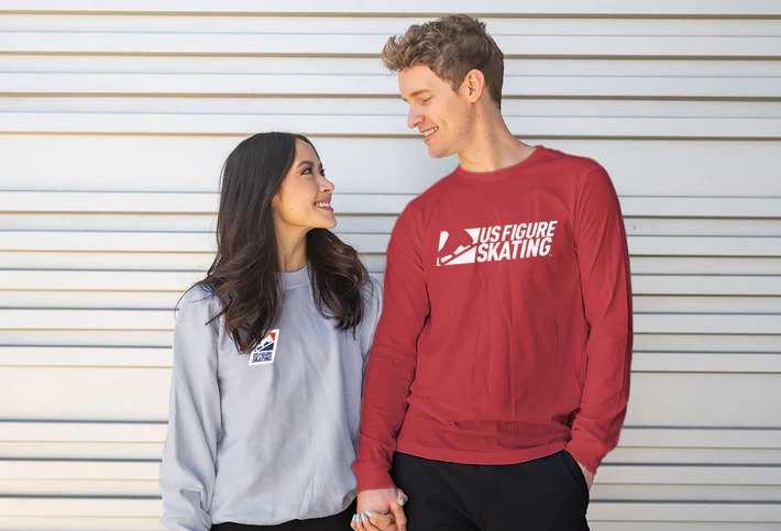 Madison Chock and Evan Bates hold hands anf look at each other as they model U.S. Figure Skating sweatshirts. 