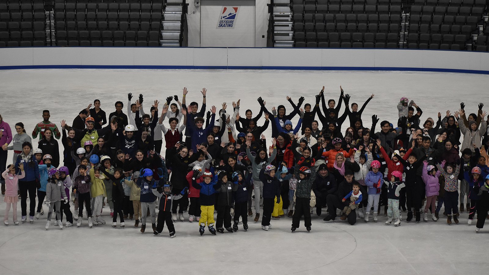 Dozens of skaters stand in the middle of the SC of Boston Tenley Albright Performance Center as part of World Ice Skating Day.