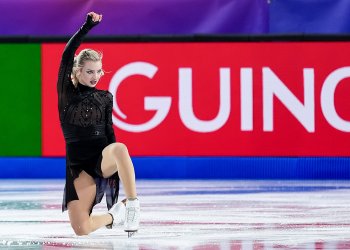 Wearing all black, down on one knee, one arm extended, Amber Glenn shows deep conviction at the Grand Prix Final