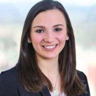 Headshot of Jordan Alexander. She is a woman with shoulder length brown hair wearing a white top and a black blazer