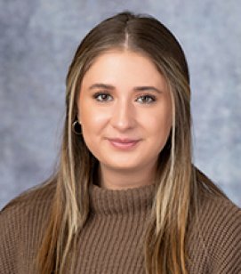 Headshot of a Courtney Burson. She is a Caucasian woman with long brown hair. She is wearing a brown turtleneck