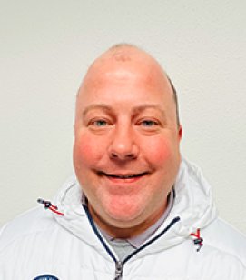 Headshot of a Caucasian man smiling. He is bald and is wearing a navy blue shirt